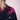 Close-up of black jacket with pink beaded floral embellishment on shoulder and blue knit hat