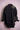 Black denim jacket with colorful floral embroidery on the upper back, displayed on pink stand