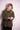 Smiling woman adjusting sleeve of brown leopard print velvet shirt with embroidered floral details