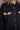 Close-up of black denim jacket with silver snap buttons and decorative beige floral embroidery on chest pockets