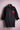 Black distressed denim jacket with red feathered bird patch on chest, displayed on pink mannequin
