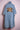 Light blue denim kimono with three embroidered teddy bears on the back, displayed on pink stand