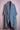 Blue denim kimono jacket with wide lapels and embroidered patches on pockets displayed on pink dress form