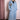 Woman wearing long light blue denim trench coat with embroidered lion face patch on chest pocket