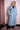 Woman wearing long light blue denim trench coat with embroidered lion face patch on chest pocket