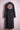 Black denim trench coat with colorful embroidered floral mandala on back displayed on pink hanger