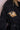 Black trench coat with gold and pearl floral brooch on lapel and waist belt detail