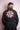 Woman wearing black trench coat with colorful embroidered floral mandala design on back
