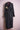 Long black denim trench coat with belt and embroidered gold applique on pink dress form