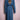 Back view of long blue denim trench coat with tiger face embroidery and belt on pink mannequin